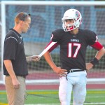 Former head football coach Adam Grimes (left) talks with junior quarterback Nate Ostmo during the Cards' 41-26 loss to Wilson on Aug. 30.