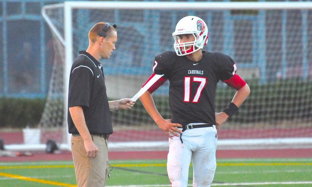 Former head football coach Adam Grimes (left) talks with junior quarterback Nate Ostmo during the Cards 41-26 loss to Wilson on Aug. 30.