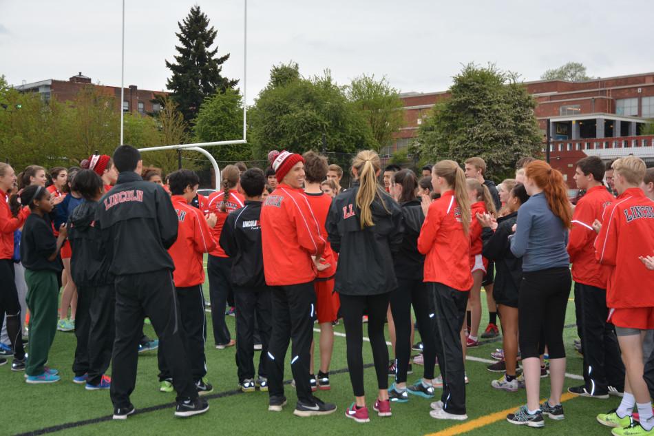 The track team finishes its warm-up by clapping and yelling Cards! at a home meet against Aloha on April 16.