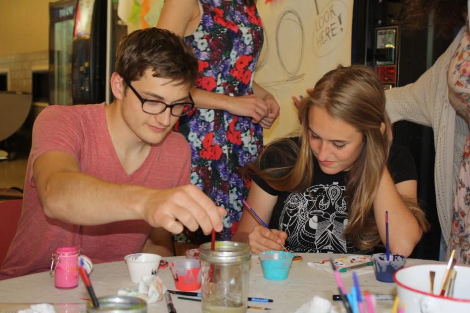 Quin Gattey and Annie Savaria-Watson paint acts of kindness and Mexican designs on pottery disks at the annual Arts Beat May 30.