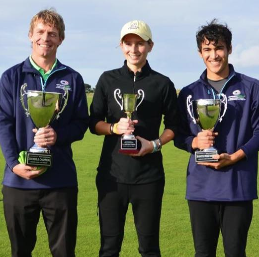 Ben Stickney (right) holds his world championship trophy alongside Eri Crum (left) and Gretchen Johnson.