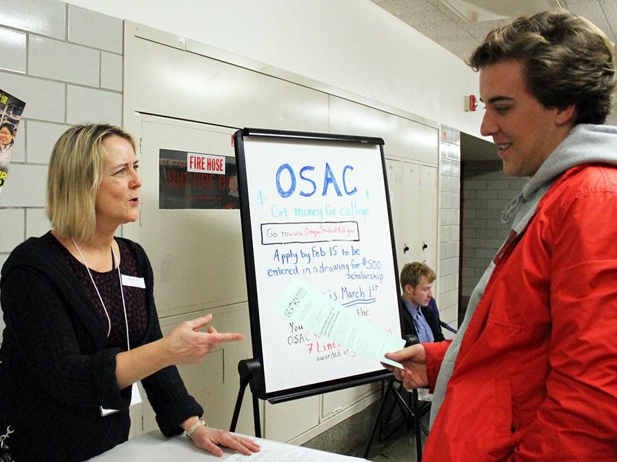 Renae Lind, parent and school coordinator, explains OSAC scholarships to senior Sam Flecker.