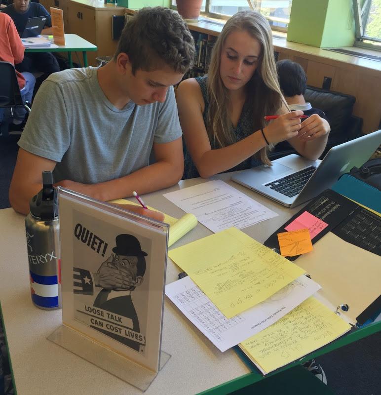 Sophomore Connor Nelson and senior Annie Savaria-Watson study quietly in the library. The informational signs in the library are modeled after WWII-era propaganda posters, such as this one with the motto “loose talk can cost lives.” 