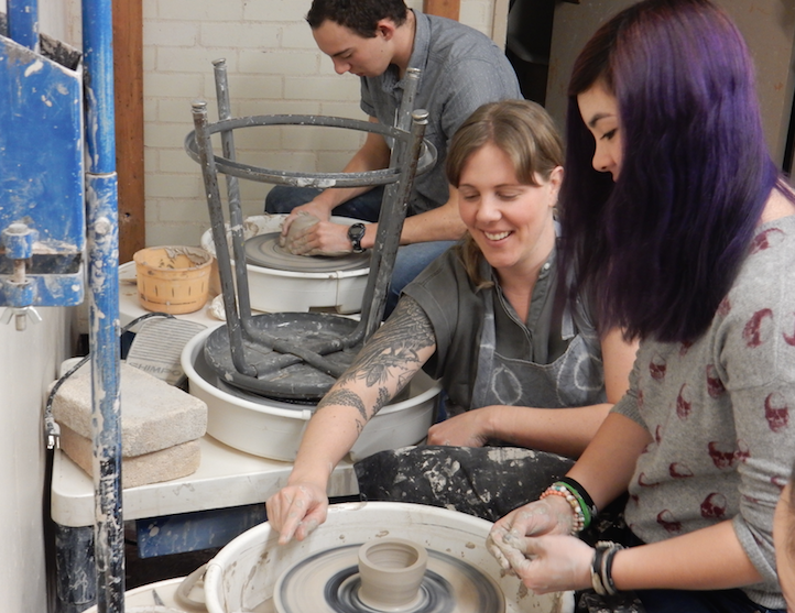 Abby Kessler assists student Bailey Smith on the pottery wheel.