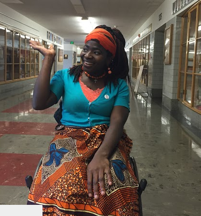 Yatta Barnett smiles and waves candidly as she rides down main hall.