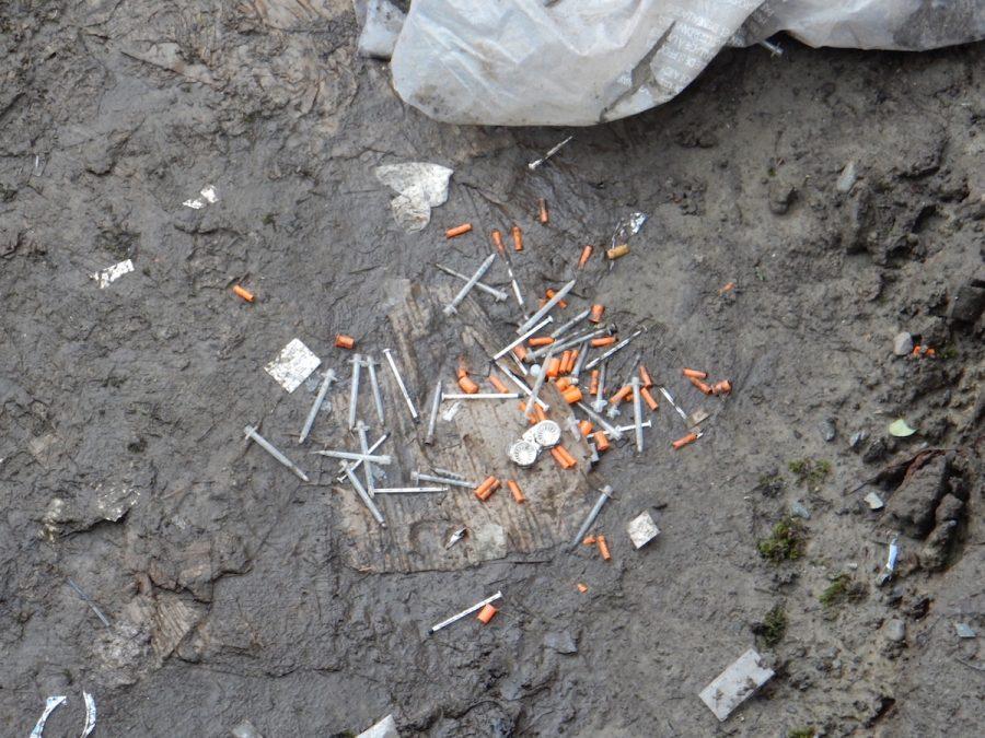 A pile of needles lies among other garbage on the embankment next to the I-405 overpass. A man overdosed from heroin on the Lincoln campus June 16.