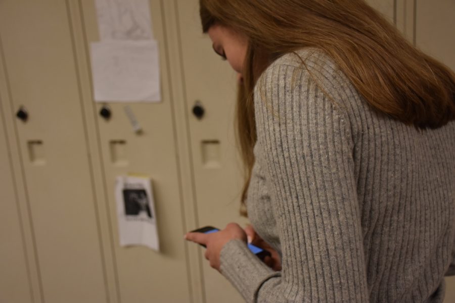 Junior Libby Lazzara sends a text while standing in the hall. Texting threatens students’ posture, according to several studies.