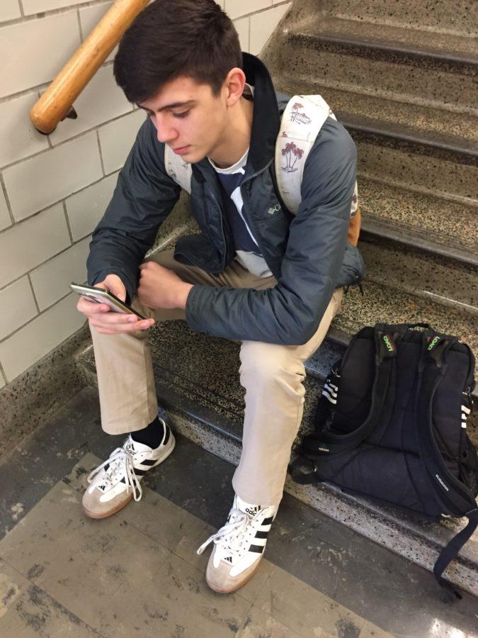 Junior Jacob Jedynak uses his phone in the hallway.