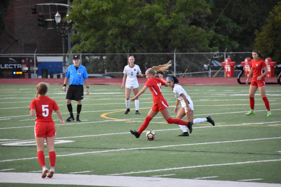 Junior Jolie Maycumber keeps the ball away from a defender during a varsity girls' soccer home game against Glencoe on Sept 12. Lincoln won 9-0. Along with girls soccer, other fall sports are underway, and coaches and players are excited for the season to come.