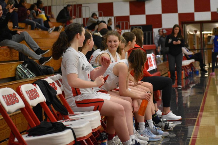 Freshman Morgan Miller, right, chats on the bench with her teammates during a varsity basketball game.