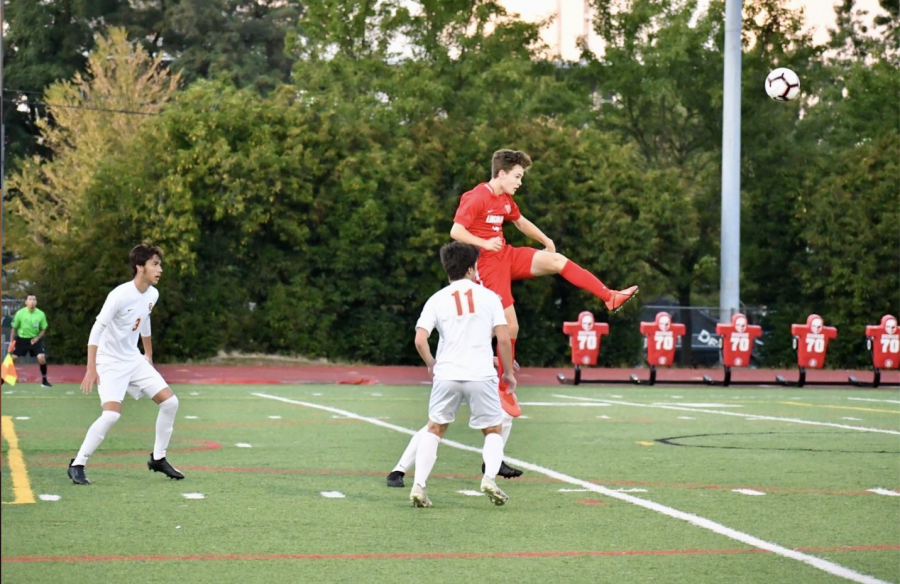 Senior Aidan McCabe leaps up above an opponent in a varsity soccer game at Lincoln last fall.