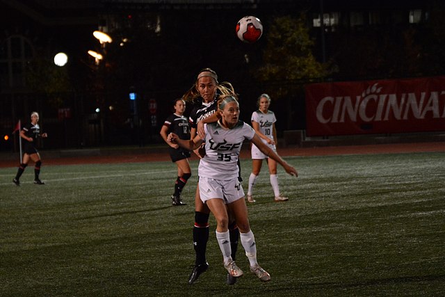  Sydny Nasello (in white), goes up for a header in a match against the Cincinnati Bearcats. The Portland Thorns draft pick is facing backlash from Portland Thorns fans for reposting tweets against anti-trans athletes. 