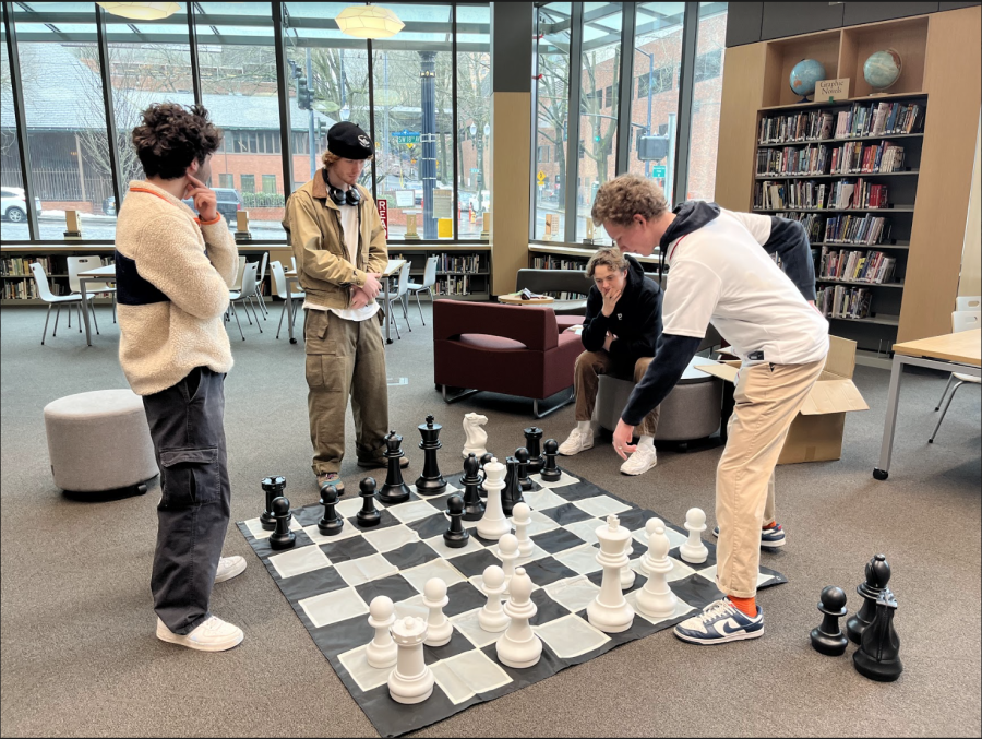 Junior Lucas Nims plays a game of real-life chess in the library. The huge chess board was available for students to play during lunch and free periods.