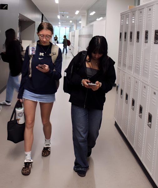 Students walk through the hallway on their phones after class. Lincoln's new phone policy requires students to lock their phones in a box for each class period.